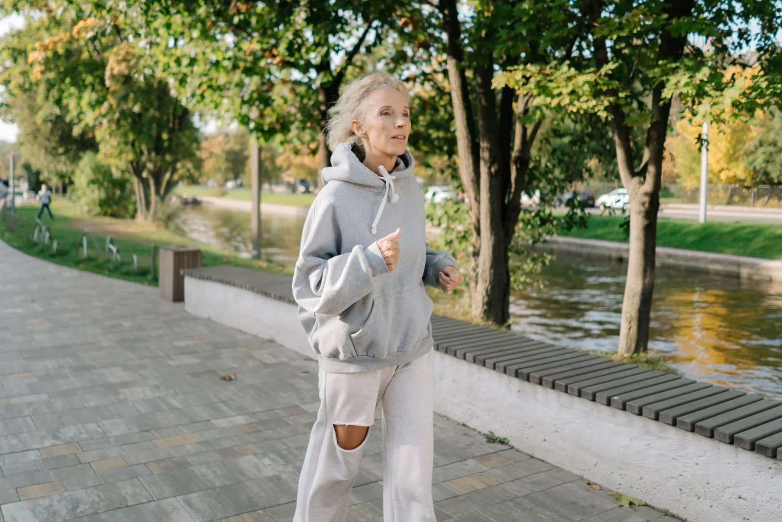 Older woman jogging along a canal path in the park