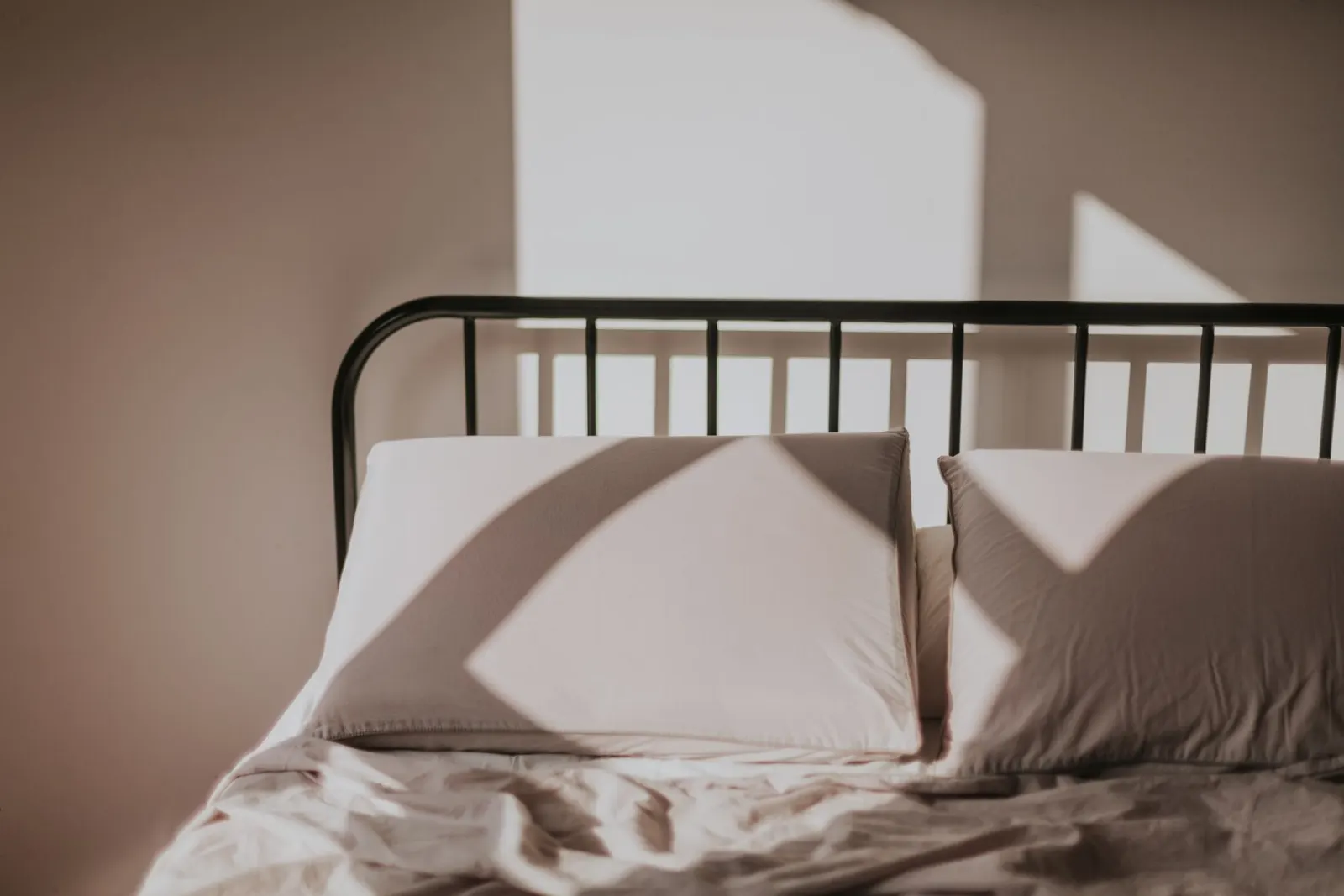 Sunlight casting soft shadows across pillows on a made bed