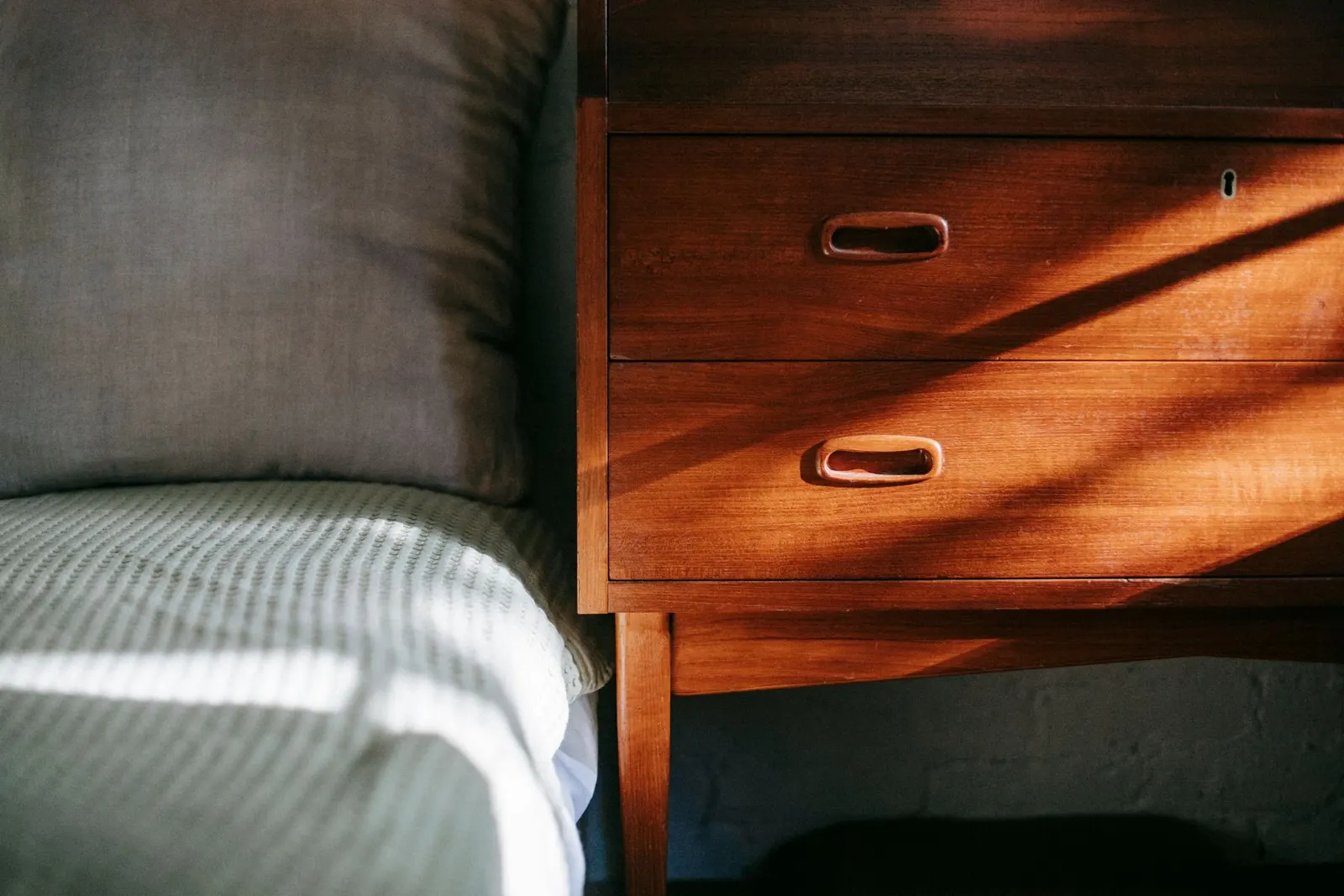 Tidy bedroom with a wooden nightstand and a bed made with a soft blanket